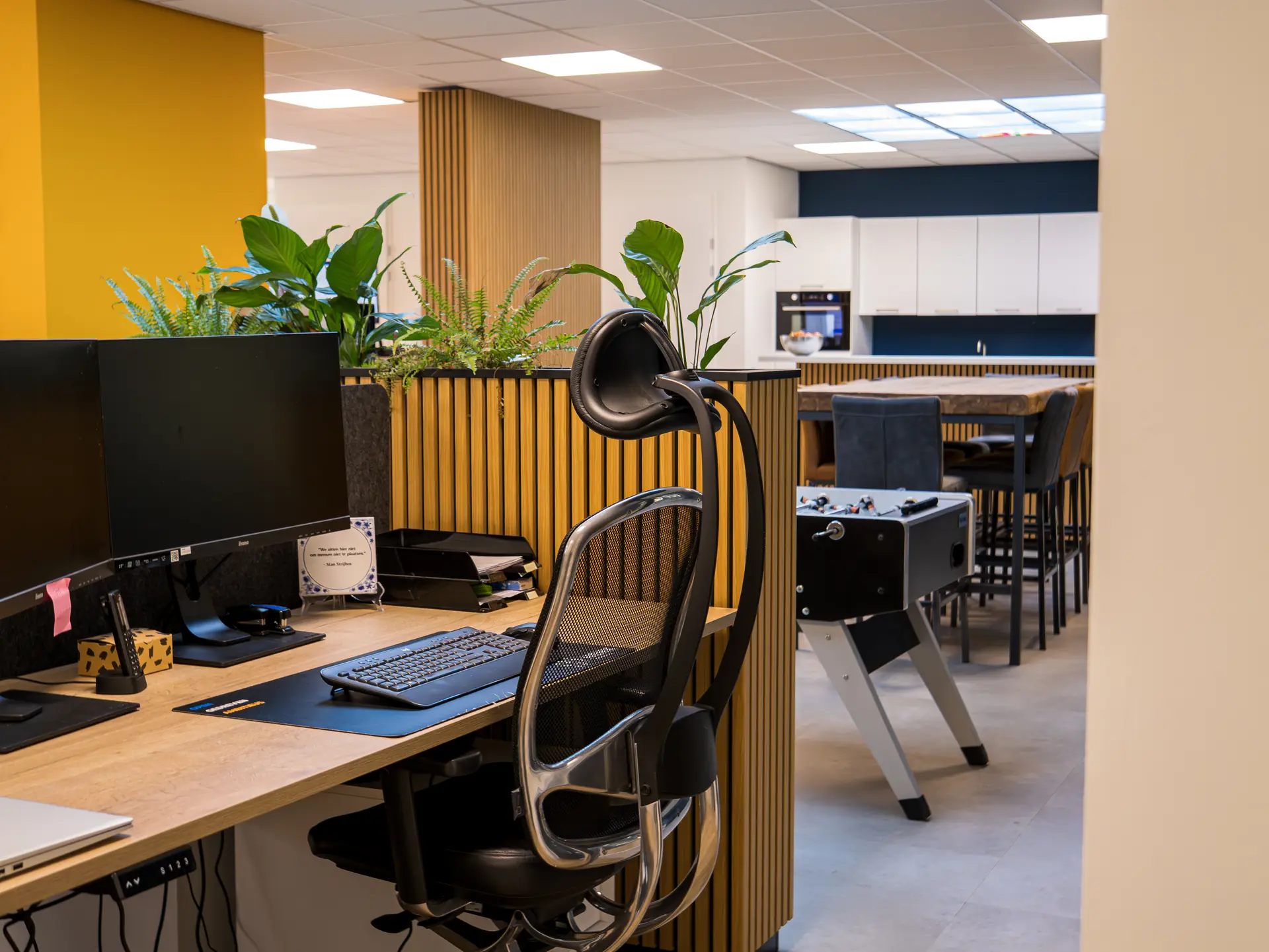Werkplekken in het kantoor van HENK met planten en houten lamellen