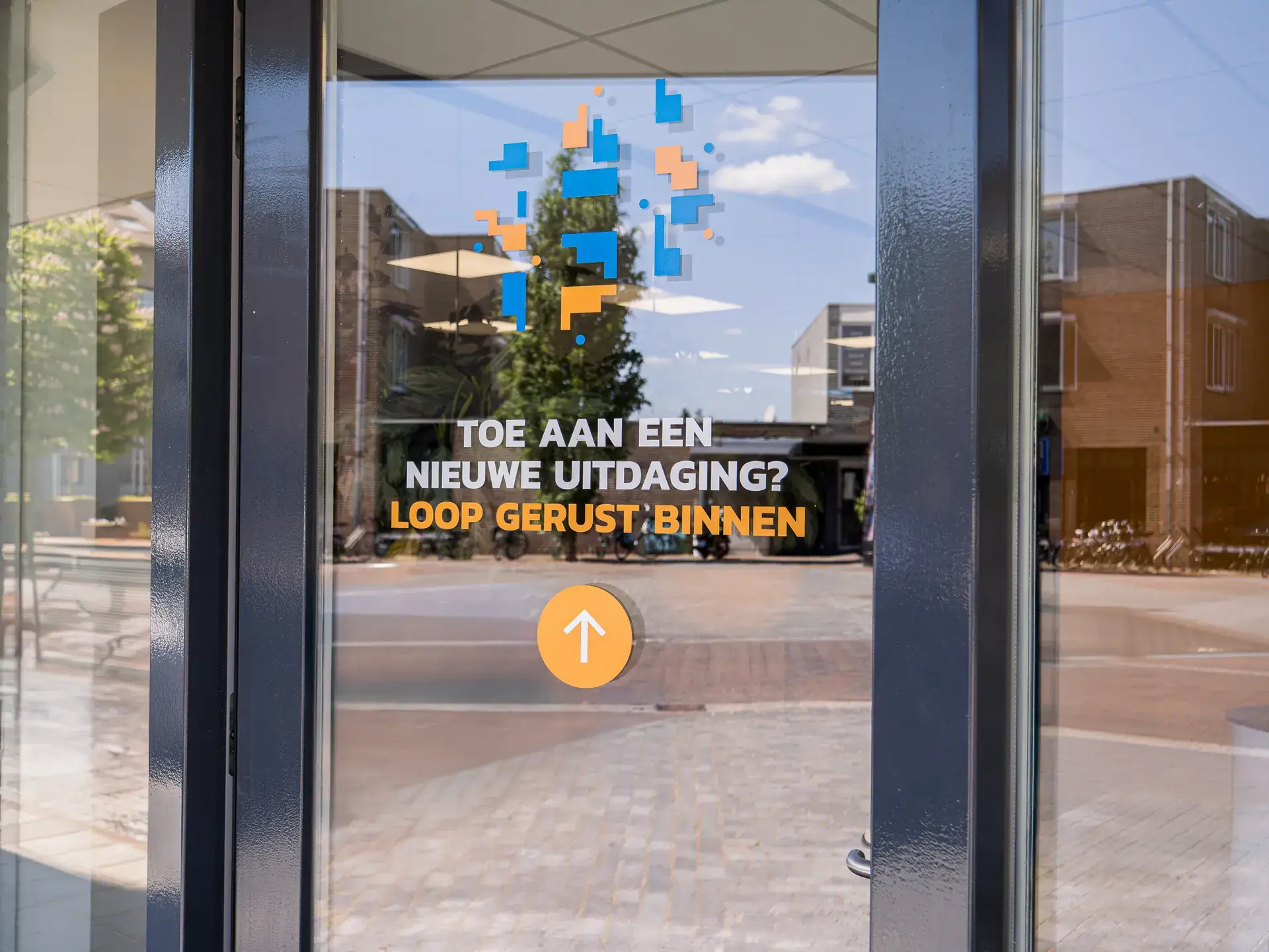 Glazen deur van HENK met de tekst ‘Toe aan een nieuwe uitdaging? Loop gerust binnen’